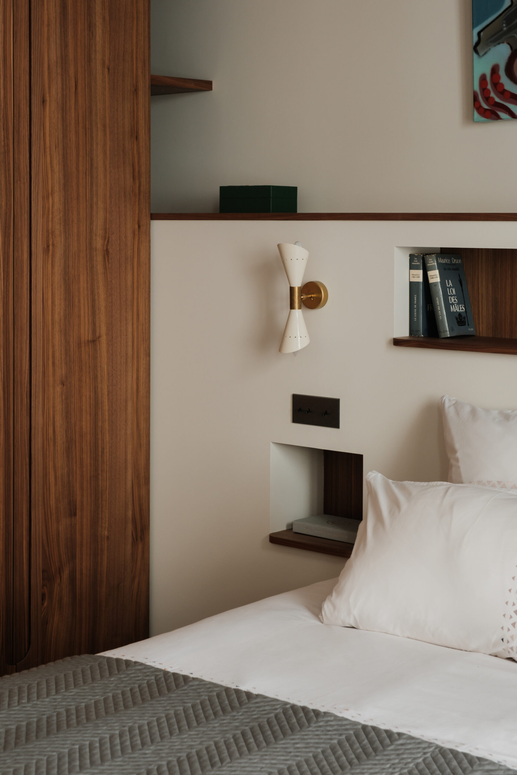 Aménagement de chambre sur mesure, dressing en noyer, tête de lit avec niches intégrées, rangements sur mesure, appliques murales en laiton, lignes épurées, matériaux nobles, design.